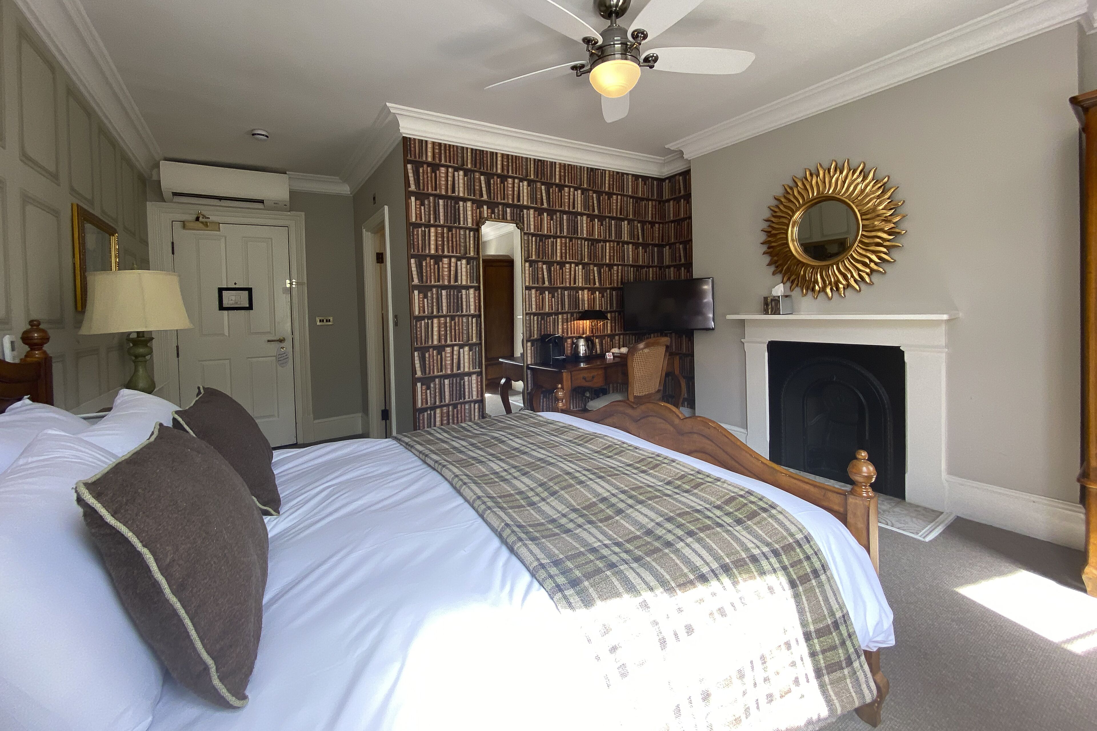 Ein Schlafzimmer mit einem großen Bett, einem Kamin, einem Bücherregal und einem Fernseher.