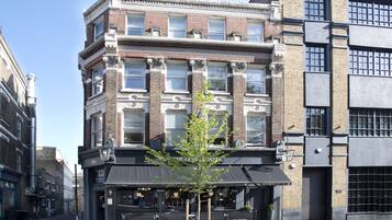 A corner building with a black awning, a tree in front, and a sign reading "The Claw Well".