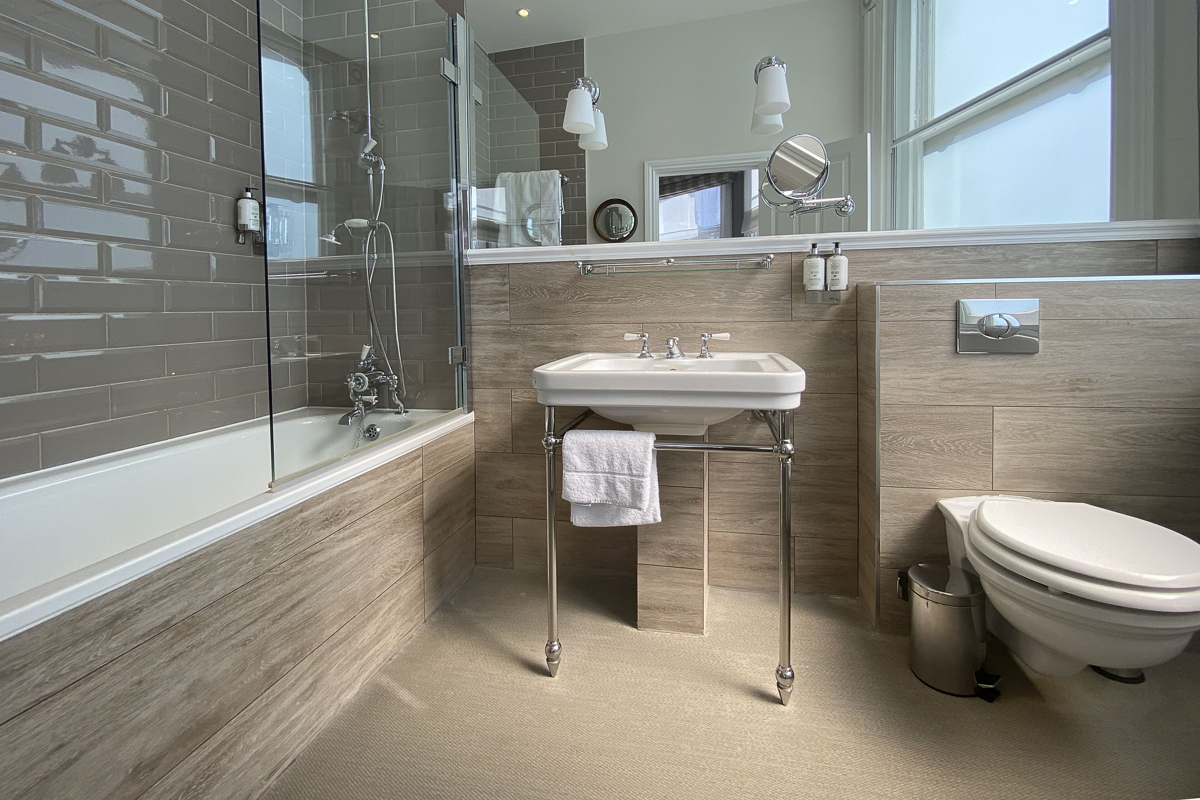 Een moderne badkamer met een glazen douchecabine, een vrijstaand wastafelmeubel en een toilet.