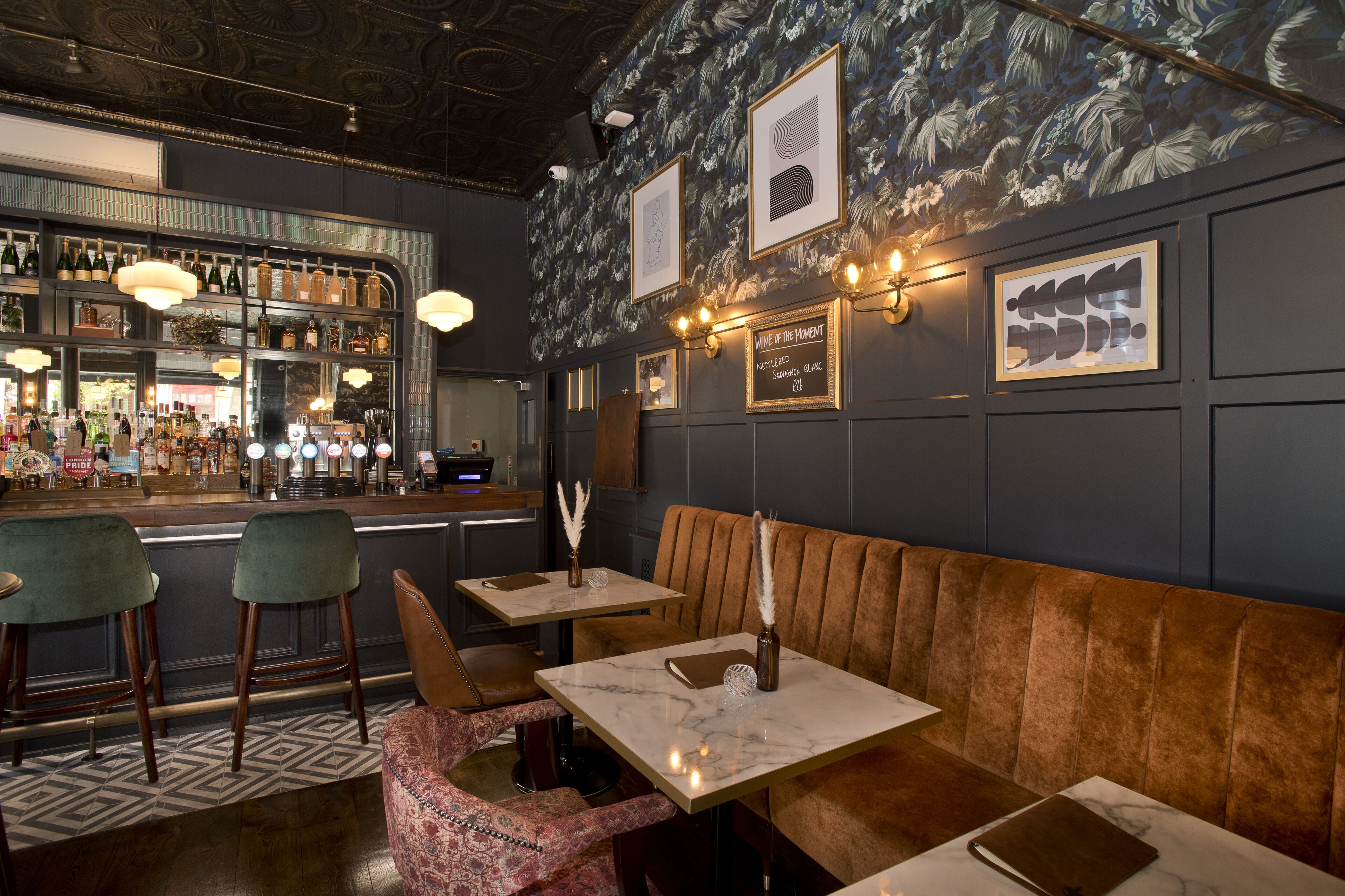 A bar area with a counter, bar stools, and a seating area with tables and a bench.