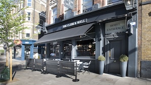 A hotel entrance with a sign reading "The Clerk & Well" and a visible entrance door. - The Clerk & Well Pub & Rooms (London)
