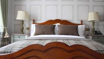 A neatly made bed with a wooden headboard, two bedside tables with lamps, and a plaid bedspread.