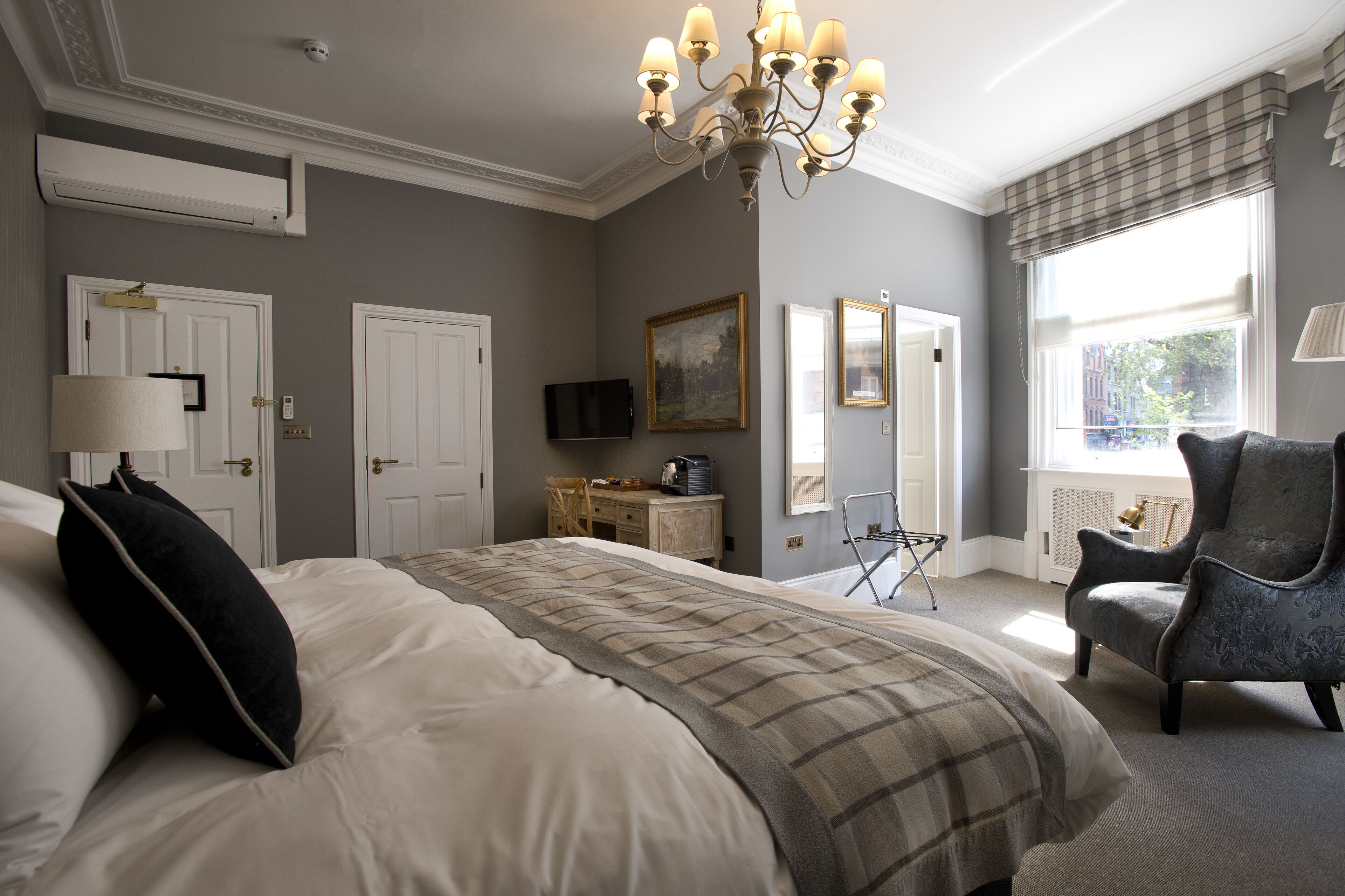 A bedroom with a large bed, a chair, a desk, a television, and a window with a view.