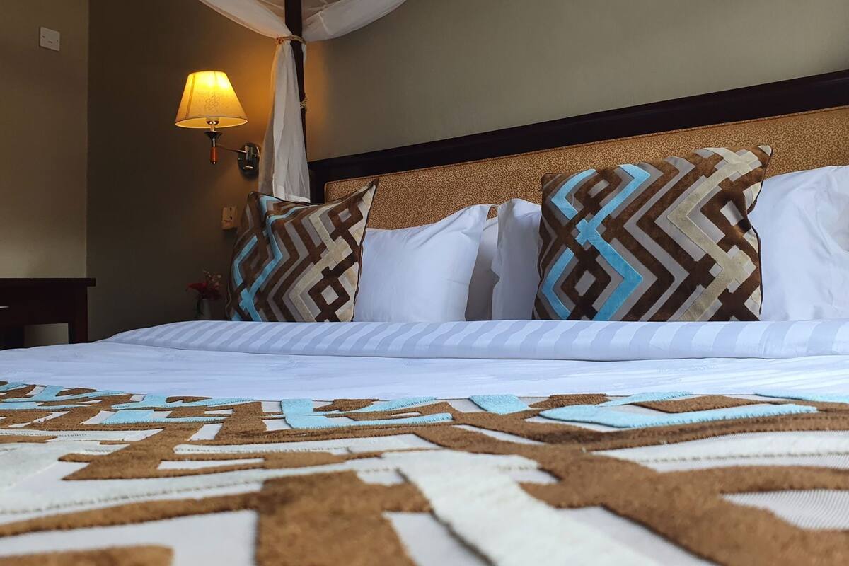 Una habitación de hotel con una cama, una mesita de noche, una lámpara y una lámpara de pared.