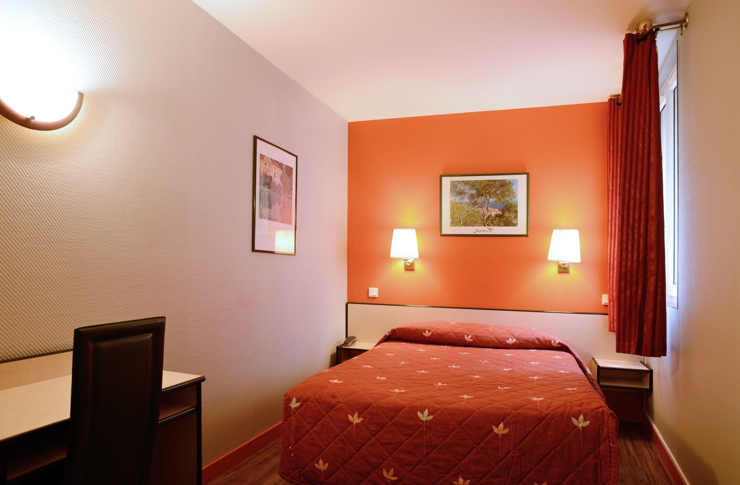 Una camera d'albergo con un letto, due abat-jour, una scrivania e una sedia.