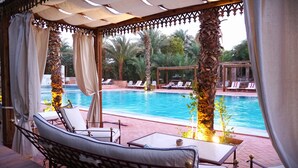 A poolside area with lounge chairs, a table, and a view of the pool. - Al Moudira Hotel (Luxor)