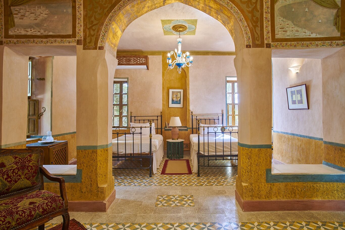 Una stanza con un letto, una sedia, un tavolo e un lampadario.