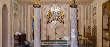A luxurious bathroom with a large bathtub, a shower, and a decorative archway.