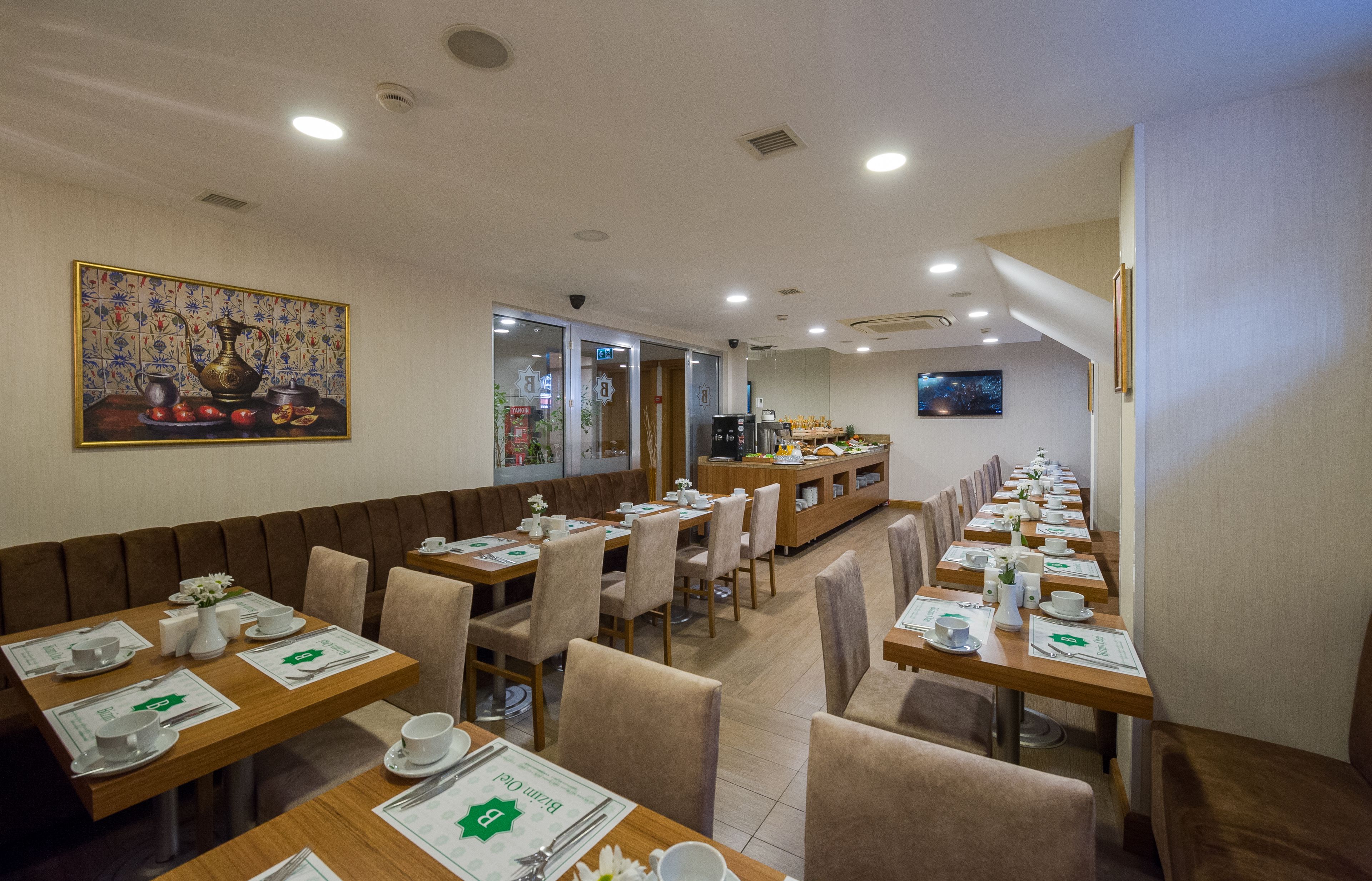 A restaurant with long wooden tables, cushioned booths, and a decorative painting on the wall.
