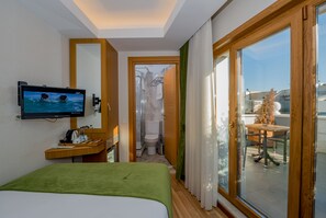 Relax in a spacious room with a large bed, flat-screen TV, and sliding glass door leading to a balcony with a view.