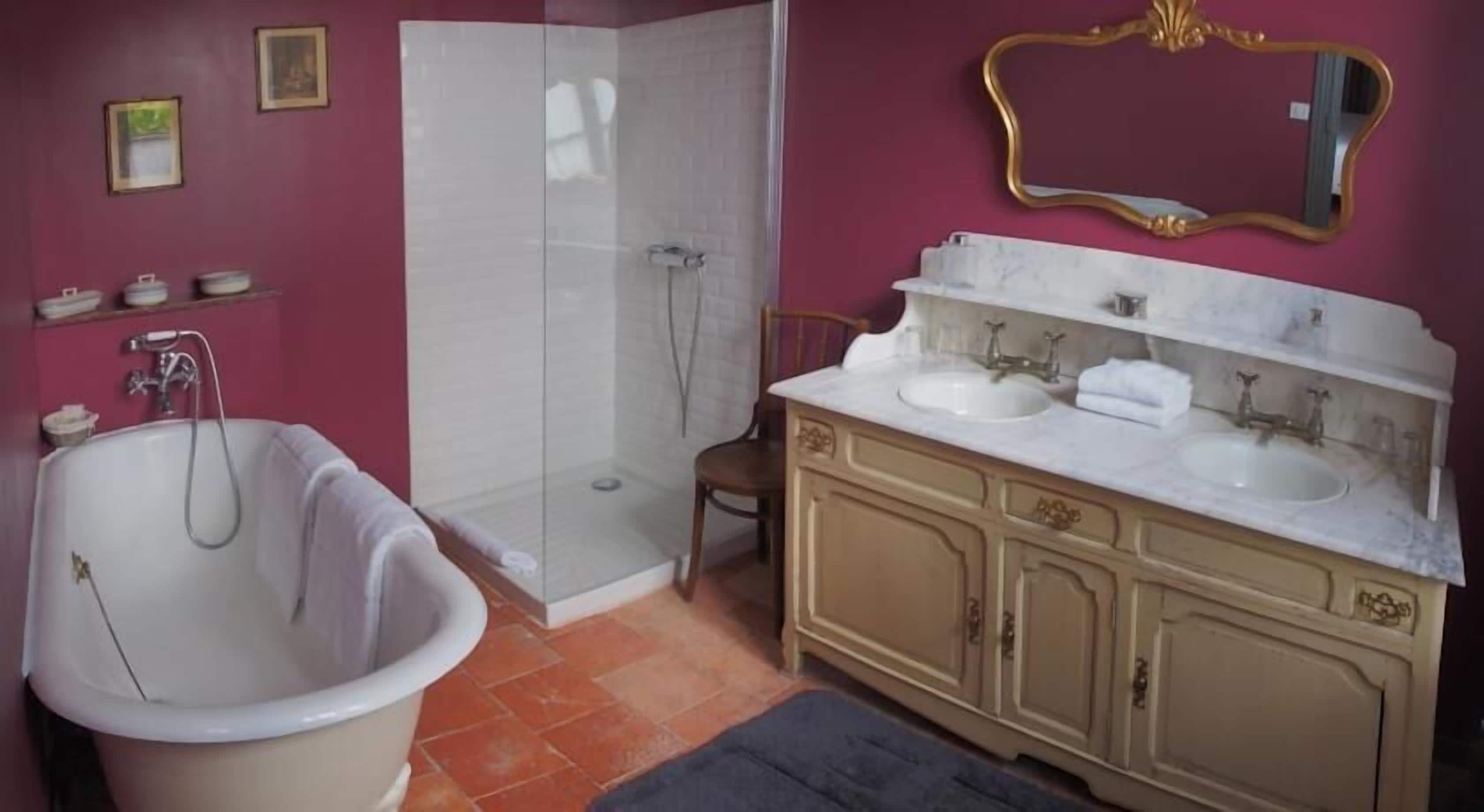 A bathroom with a bathtub, a shower, and a vanity with a mirror.
