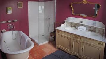 A bathroom with a bathtub, a shower, and a vanity with a mirror.