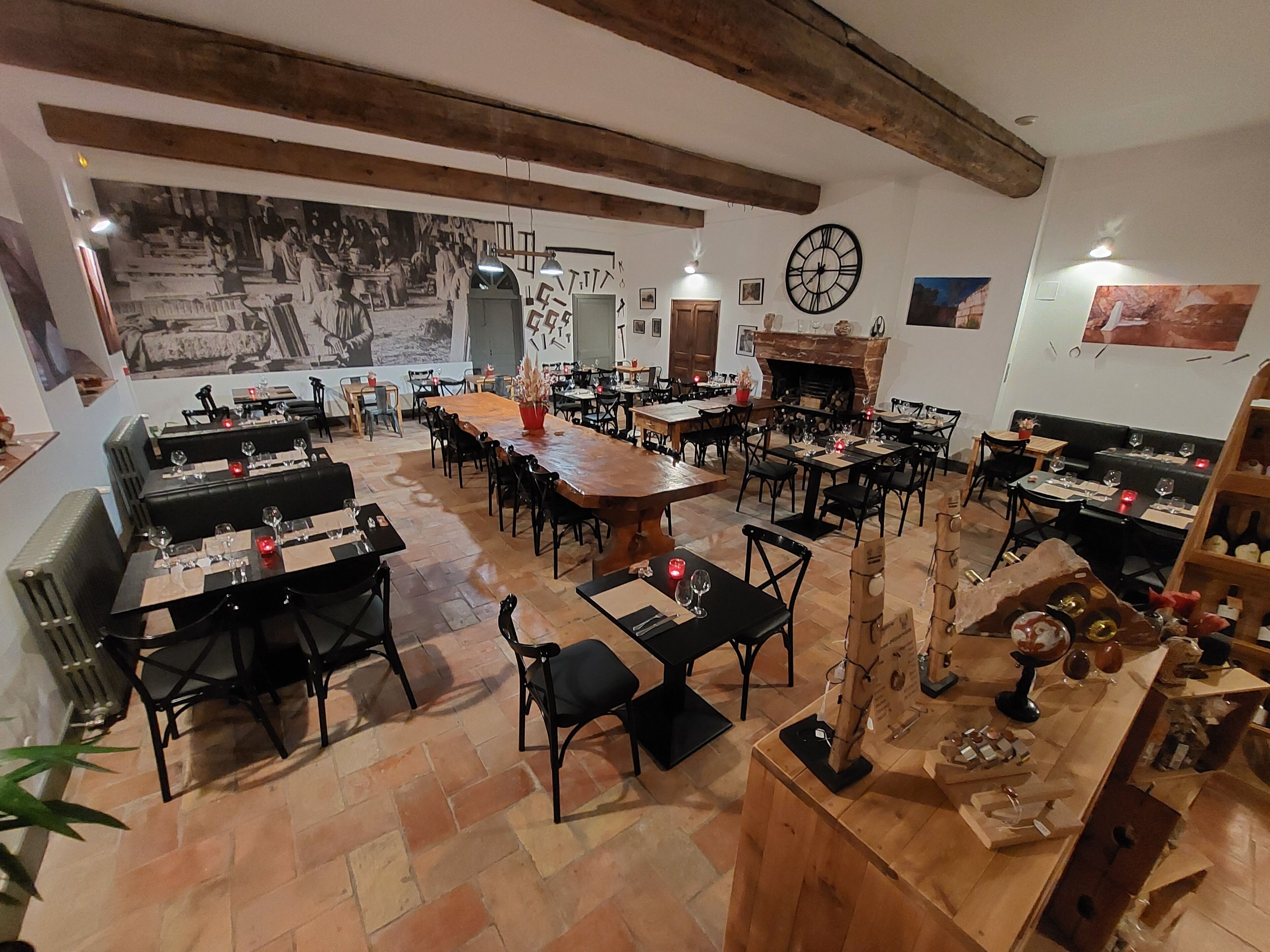 A restaurant with a rustic interior, featuring exposed wooden beams, a large central table, and multiple seating areas.