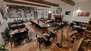 Un restaurante con una decoración rústica, con vigas de madera a la vista, una gran mesa central y varias zonas de estar.