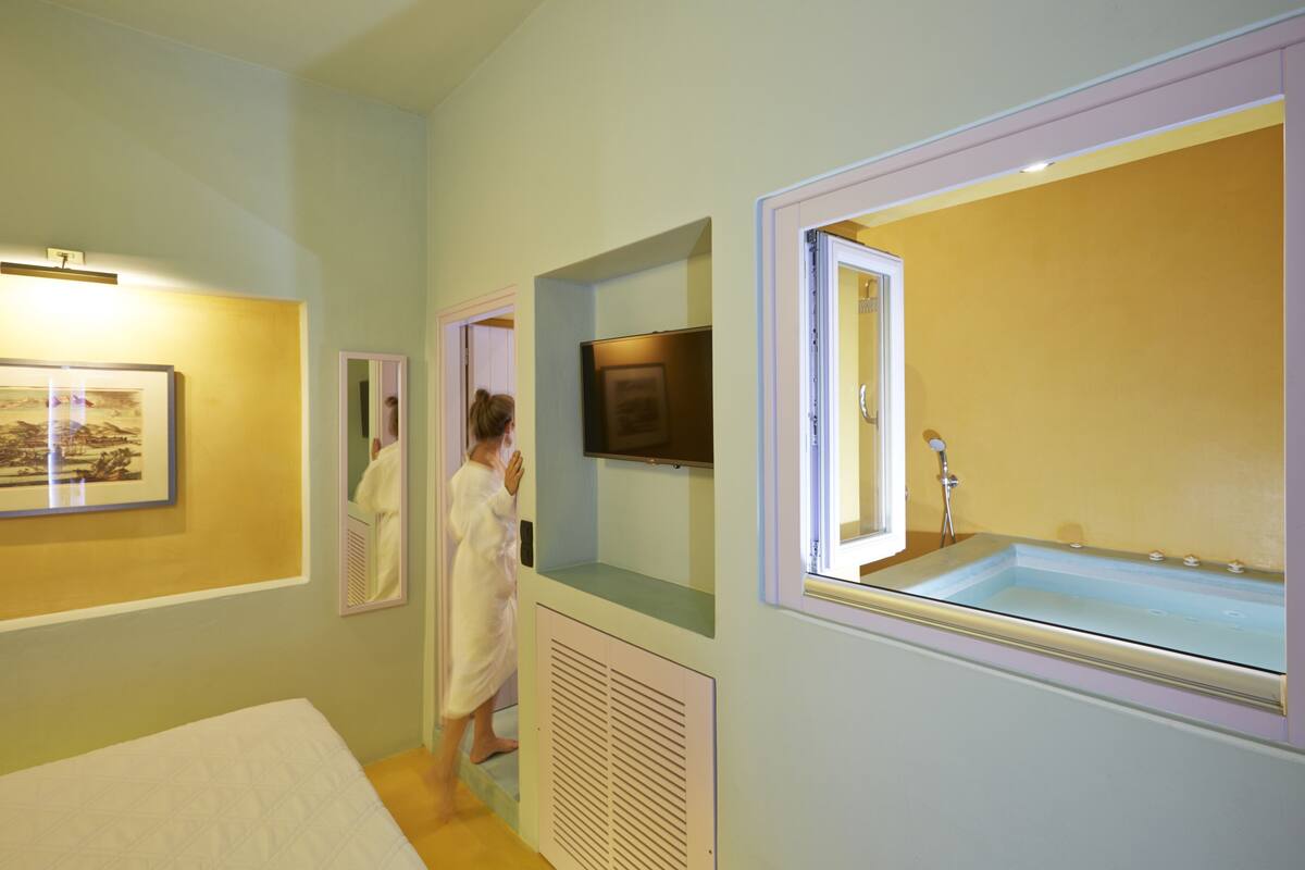 Ein Hotelzimmer mit einem großen Bett, einer Badewanne und einem an der Wand befestigten Fernseher.