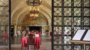 Un comedor interior con mesas dispuestas para el servicio, una araña y un atril para el menú.