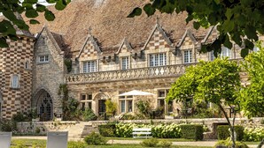 A historic building with a checkered stone facade, a central courtyard with a bench, and a garden with various plants.