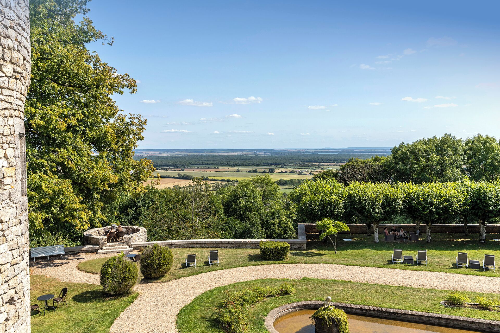 Un jardín ajardinado con muro de piedra, zonas de estar y vistas al campo.