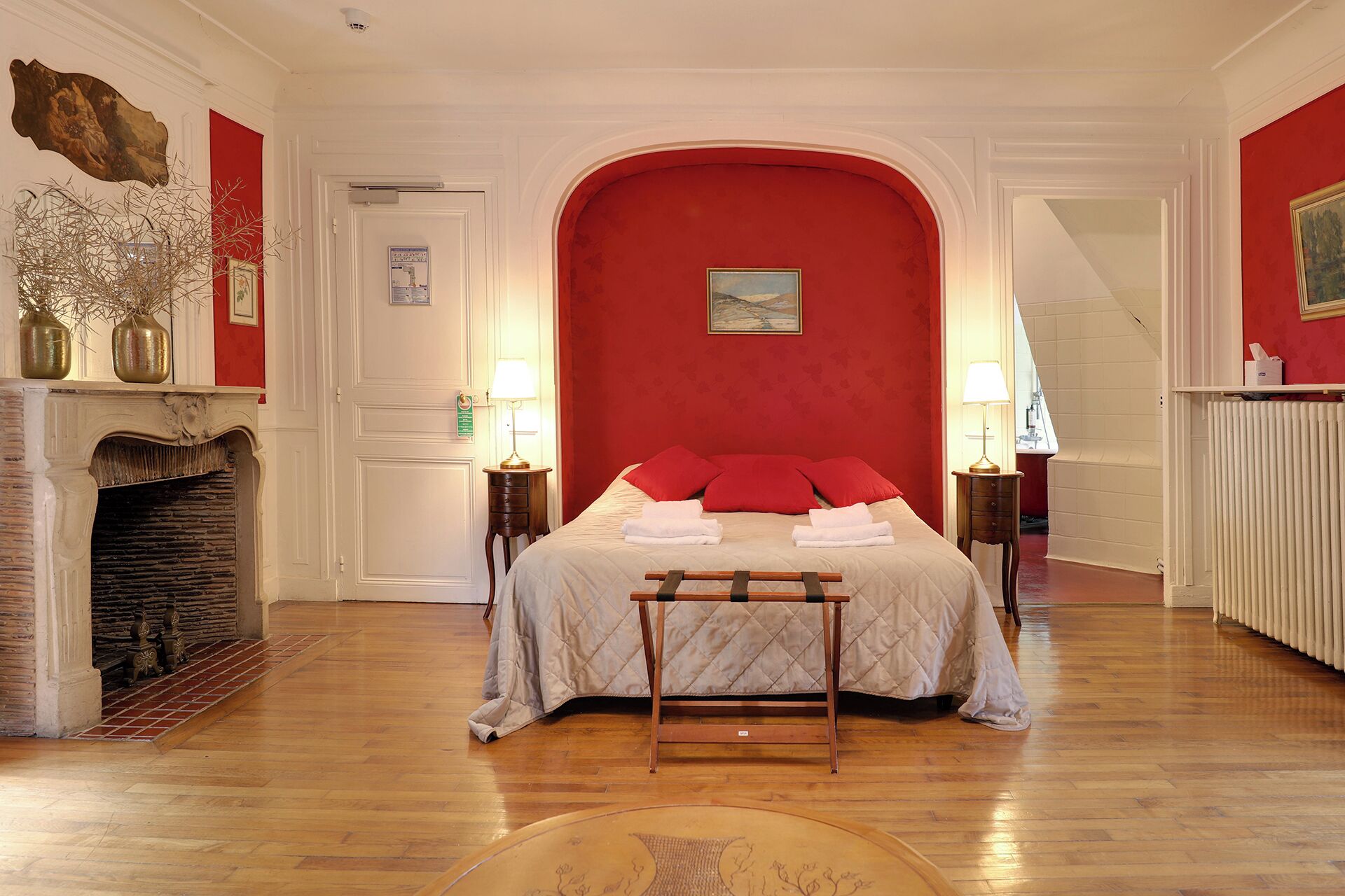 Um quarto com uma cama, lareira e parede vermelha.