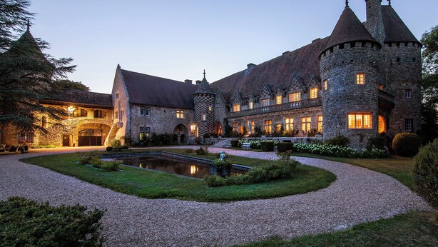 A large stone castle with multiple towers and a central courtyard with a pond.