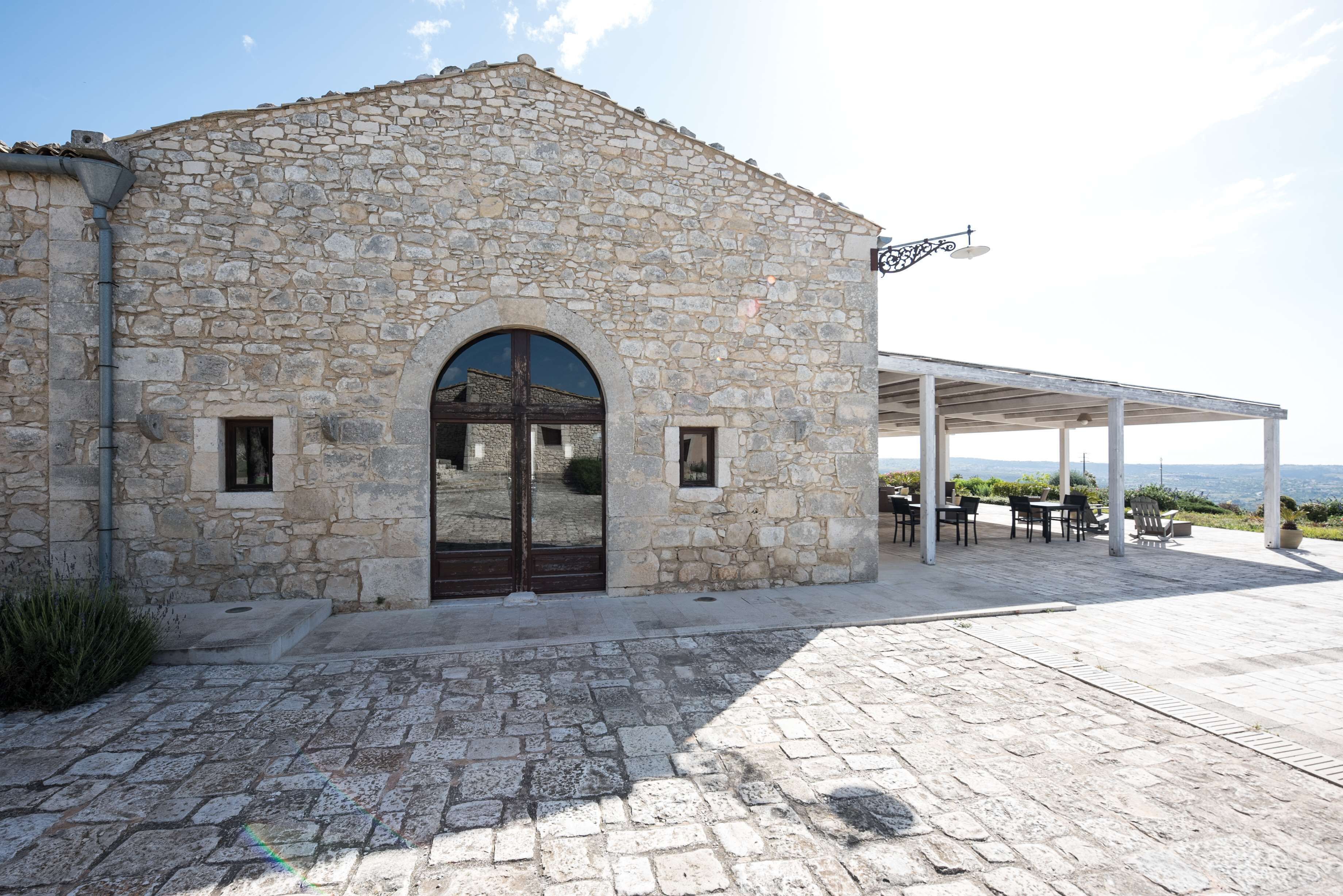 Un bâtiment en pierre doté d’un espace extérieur abrité avec des sièges et offrant une vue sur la mer.