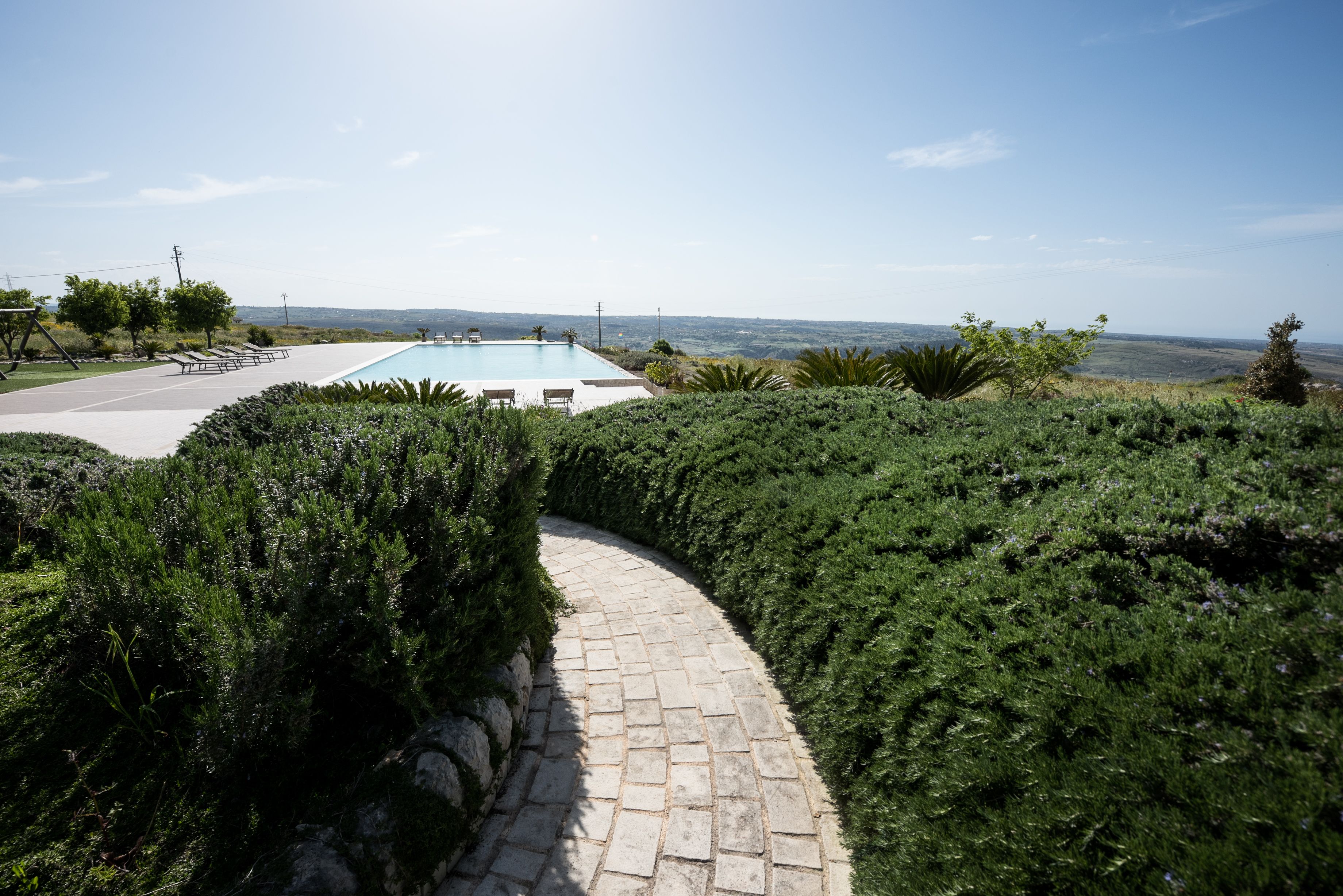 Un camino pavimentado que lleva a una piscina con vistas despejadas del paisaje circundante.