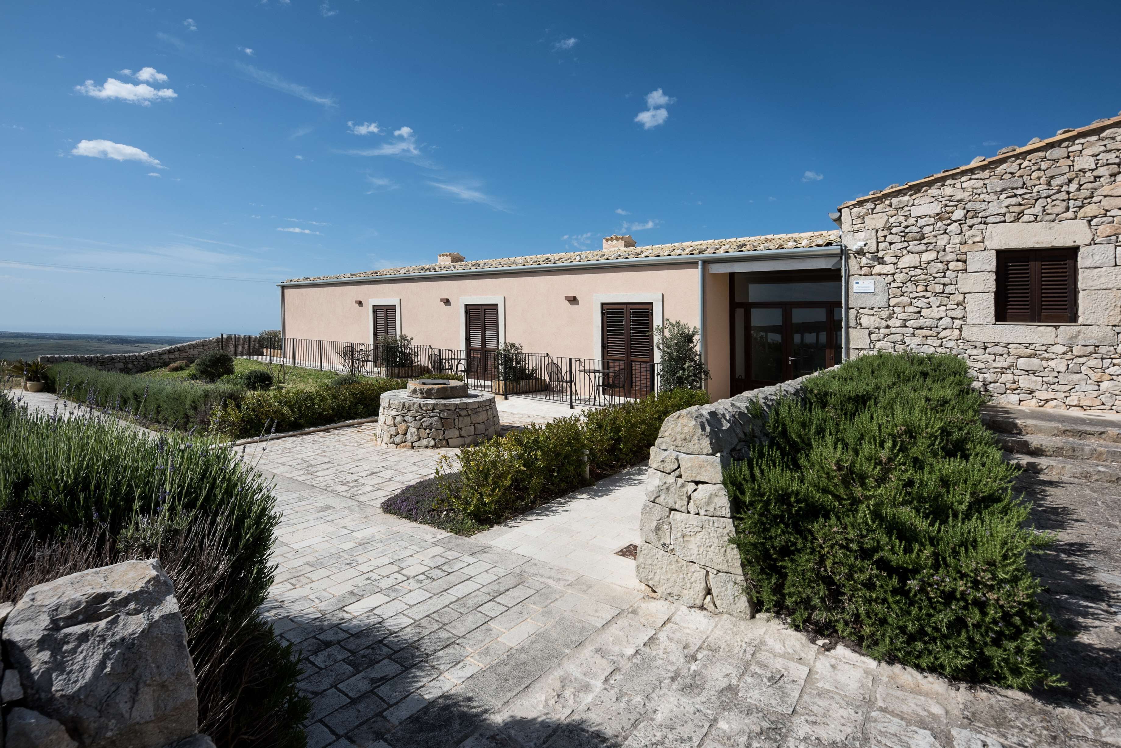 Un edificio in pietra con un cortile lastricato, mura in pietra e vista sul paesaggio.