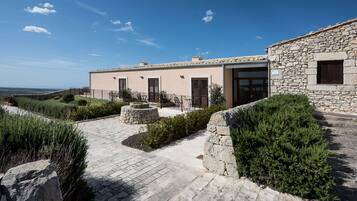Un edificio in pietra con un cortile lastricato, mura in pietra e vista sul paesaggio.