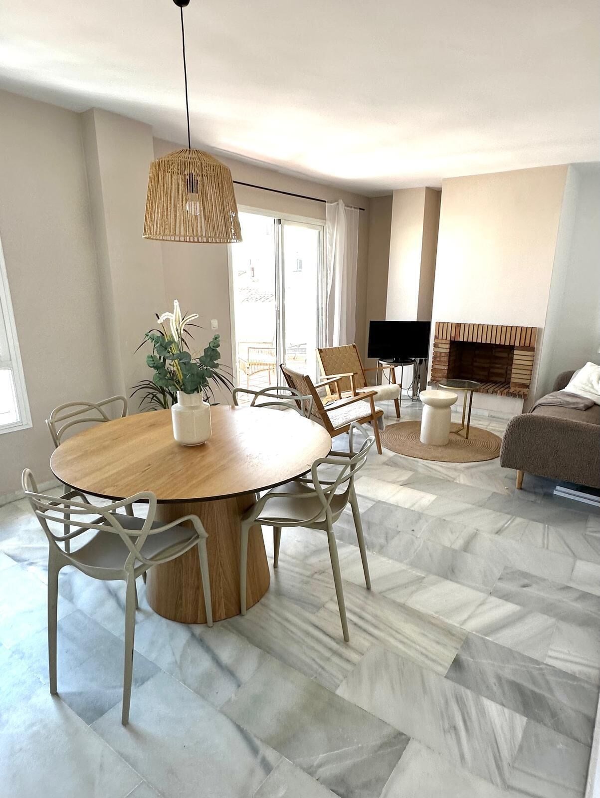 Ein stilvolles Wohnzimmer mit einem runden Holztisch, weißen Stühlen, einer Couch und einem Kamin.