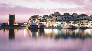 Un puerto deportivo con barcos amarrados, una torre histórica y una hilera de edificios con balcones.