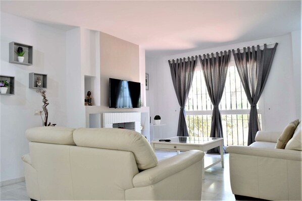 Relax in a spacious living room with a large flat-screen TV, two sofas, and a glass coffee table.