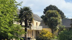 A two-story building with a balcony, surrounded by lush greenery and a well-maintained lawn. - La Demeure Du Perron (Quettehou)