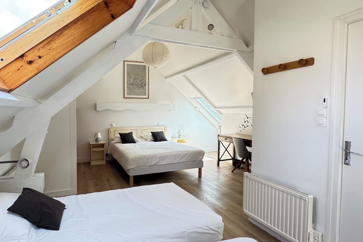 Un dormitorio con tragaluz, cama, escritorio y mesita de noche.