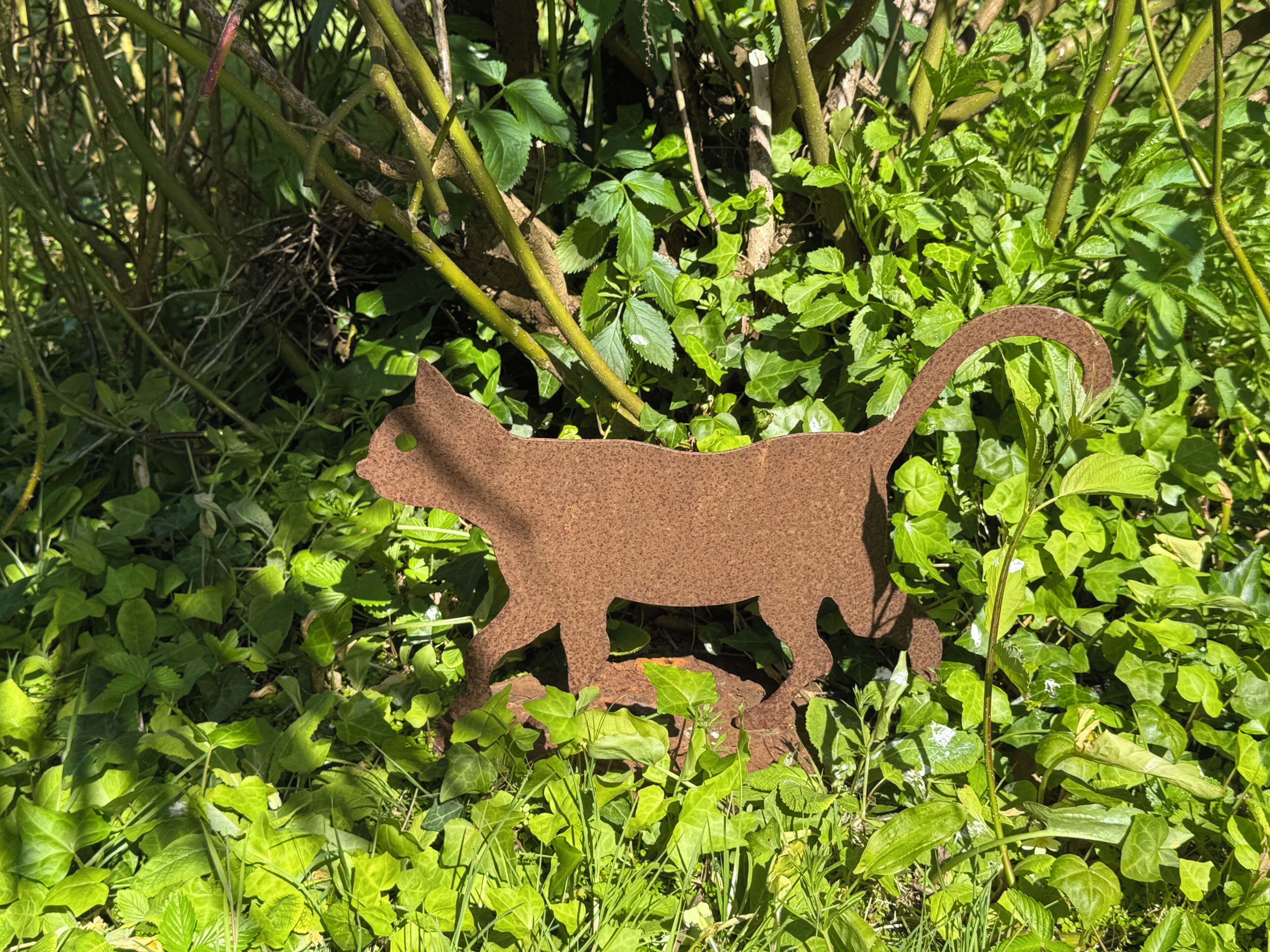 A metal cat-shaped sculpture amidst greenery.