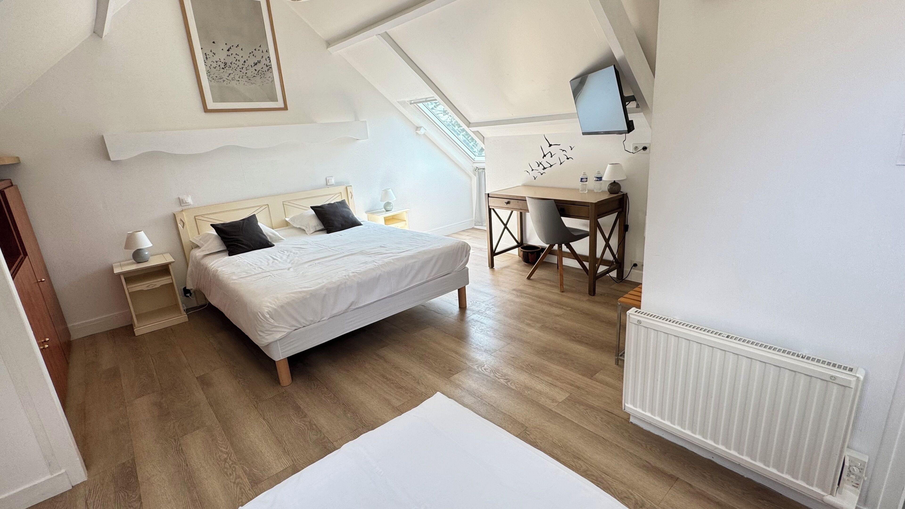 Une chambre à coucher avec un lit, des tables de chevet, un bureau et une chaise.