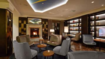 A modern lounge area with a fireplace, comfortable seating, and a bookshelf.