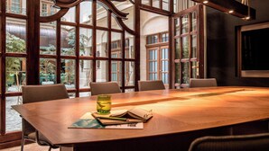 Une salle de conférence avec une grande table en bois, quatre chaises et un verre d’eau posé sur la table.