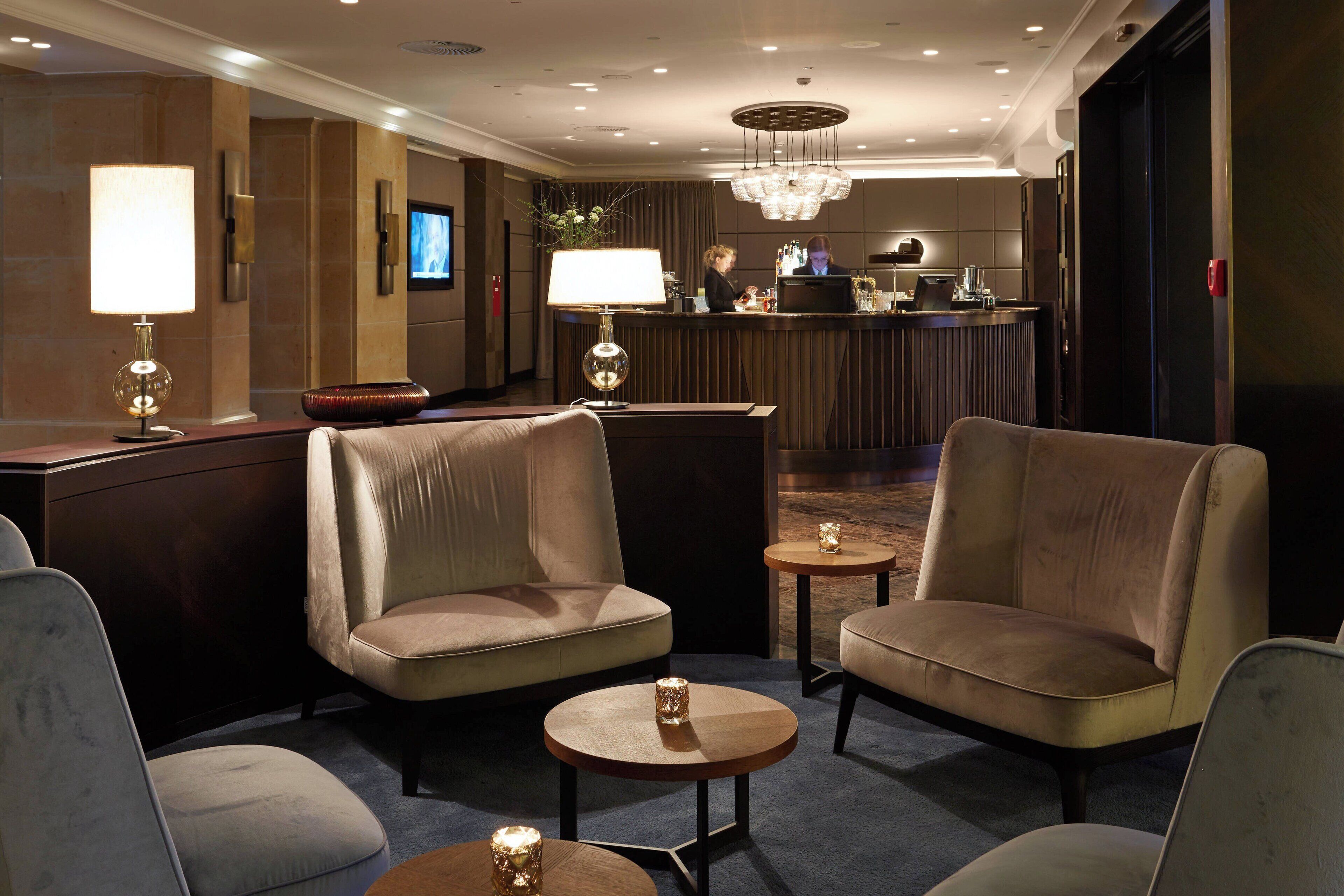 A hotel lobby with seating areas, a reception desk, and a chandelier.