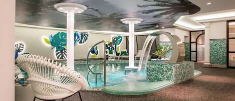 An indoor pool area with a white chair, a water feature, and a ceiling mural of palm trees.