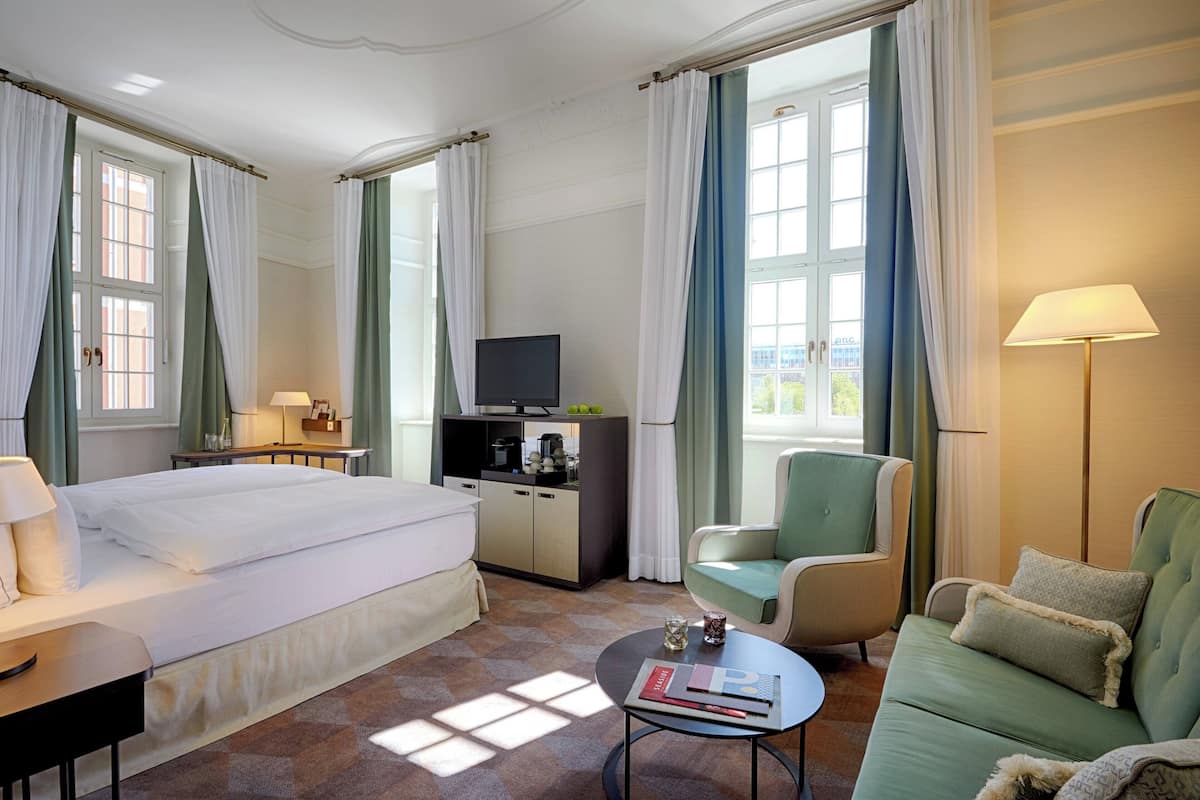 A hotel room with a bed, a sofa, a TV, a desk, and a coffee table.