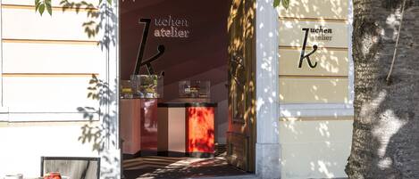 Una entrada a un edificio con un letrero que dice "Uchen atelier" y un árbol en primer plano.