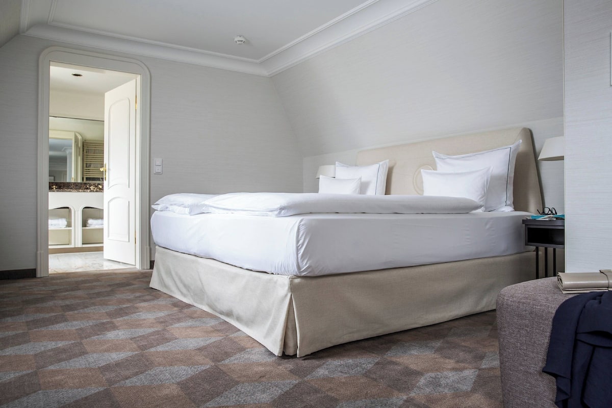 A hotel room with a large bed, a bedside table, and a chair.