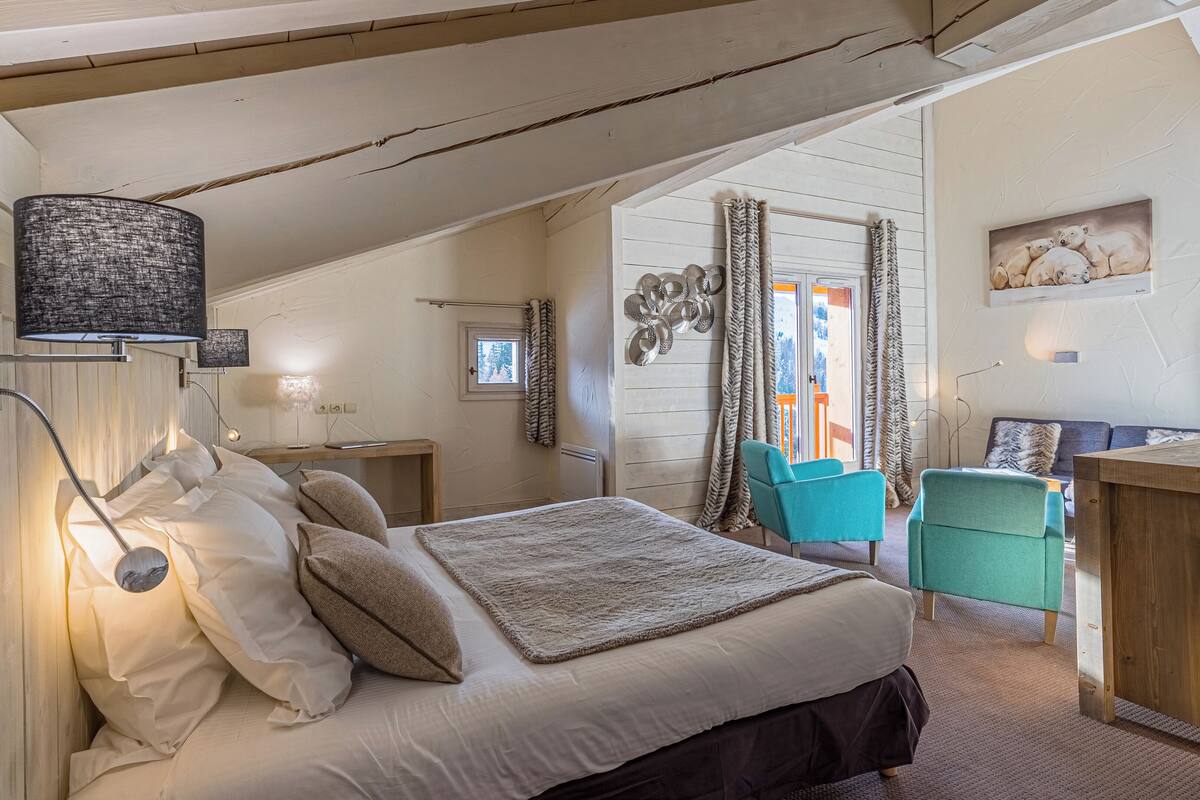 A bedroom with a bed, bedside lamp, and a desk with a chair.