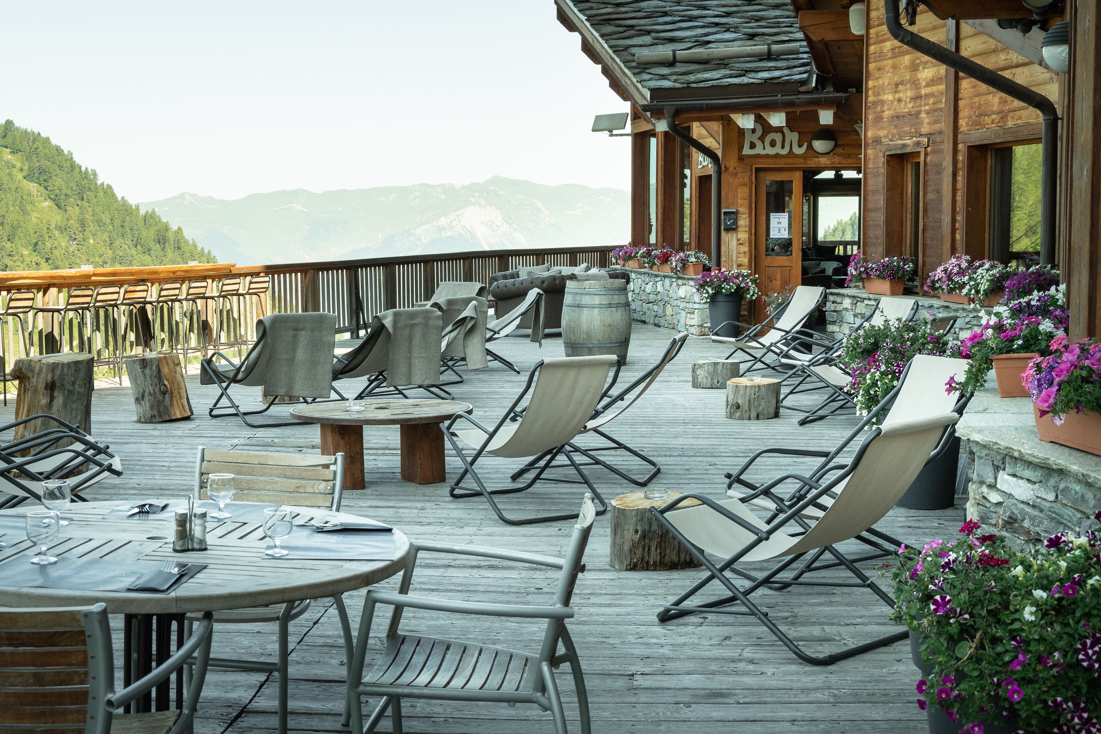 A wooden deck with outdoor seating, a bar area, and flower planters.