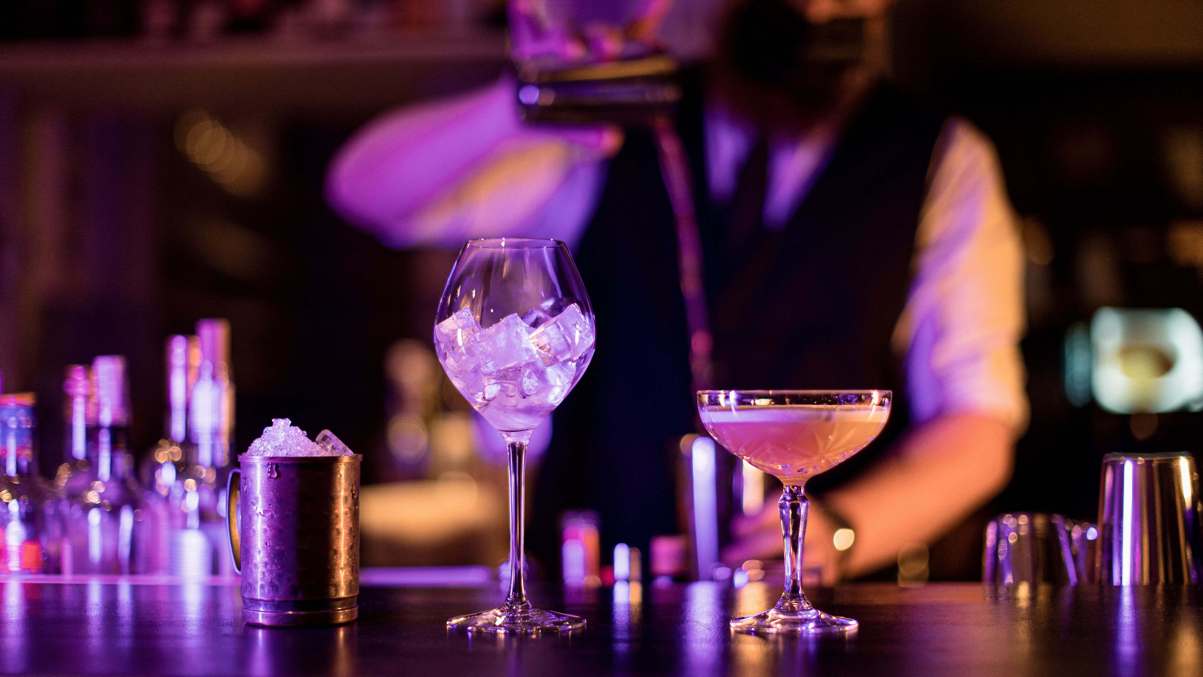 A bar with a variety of glassware, including a martini glass and a wine glass with ice.