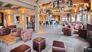 Un hall d’entrée spacieux, doté de canapés en cuir, de tables en bois et d’un coin bar.
