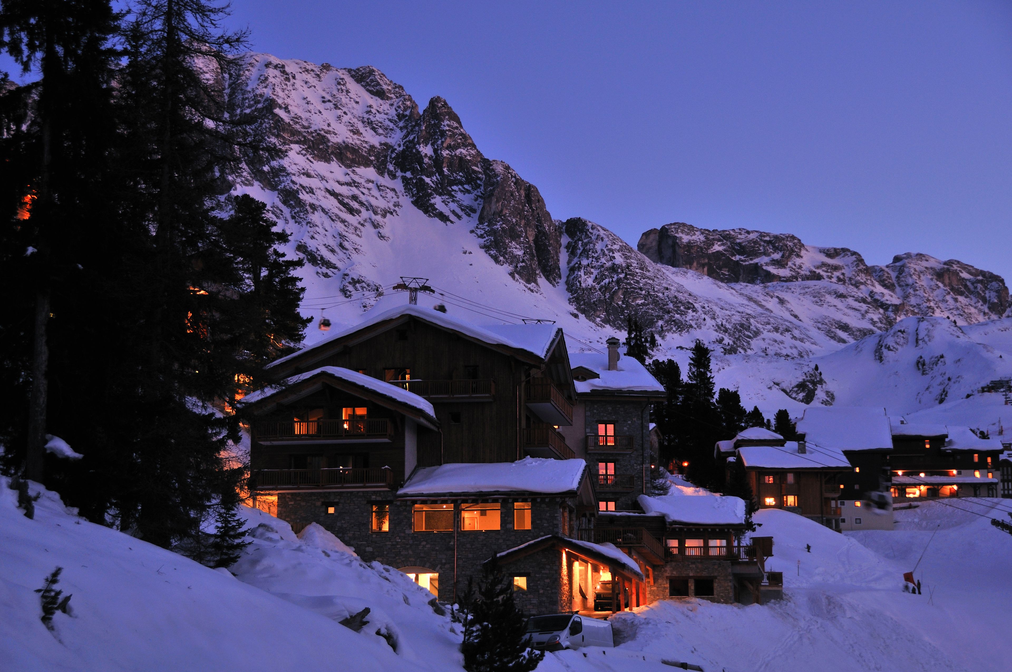 A snow-covered mountain lodge with multiple buildings, ski lifts, and a ski slope.