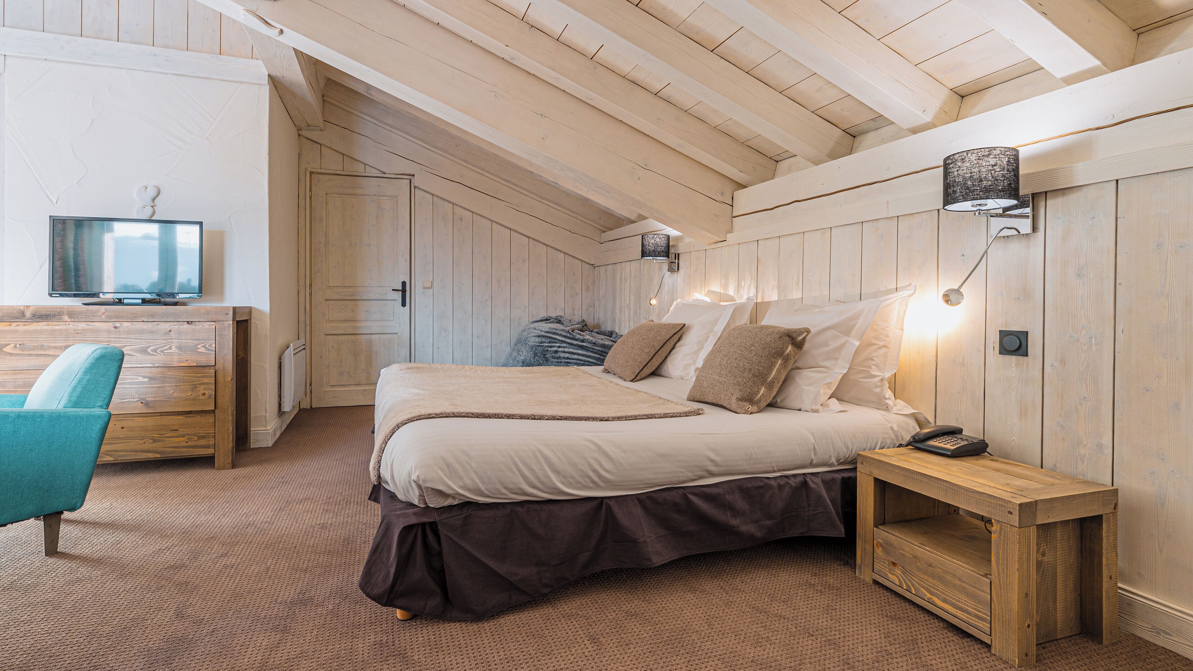 Un dormitorio con cama, mesita de noche, lámpara y escritorio con silla.