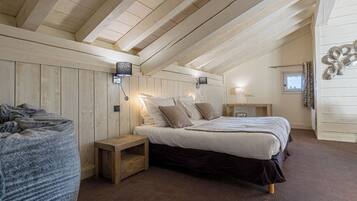 Une chambre confortable avec un plafond en bois, un lit avec une literie blanche et marron, une table de chevet et une petite table de nuit.