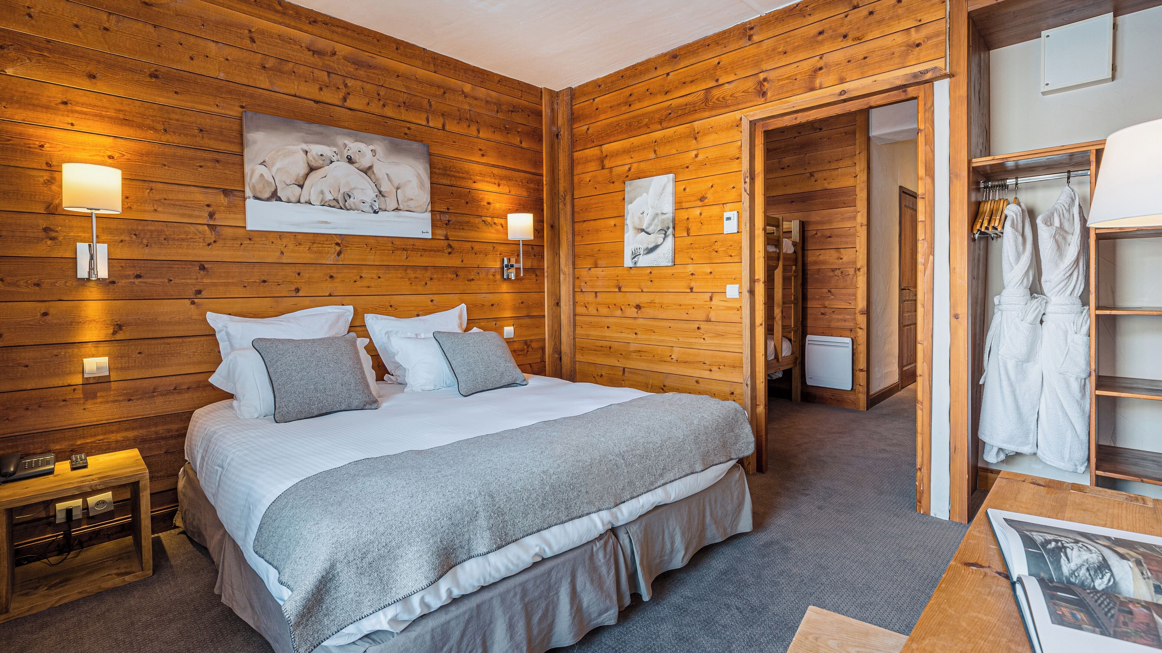 A wooden-paneled bedroom with a bed, bedside lamps, and a painting of polar bears.
